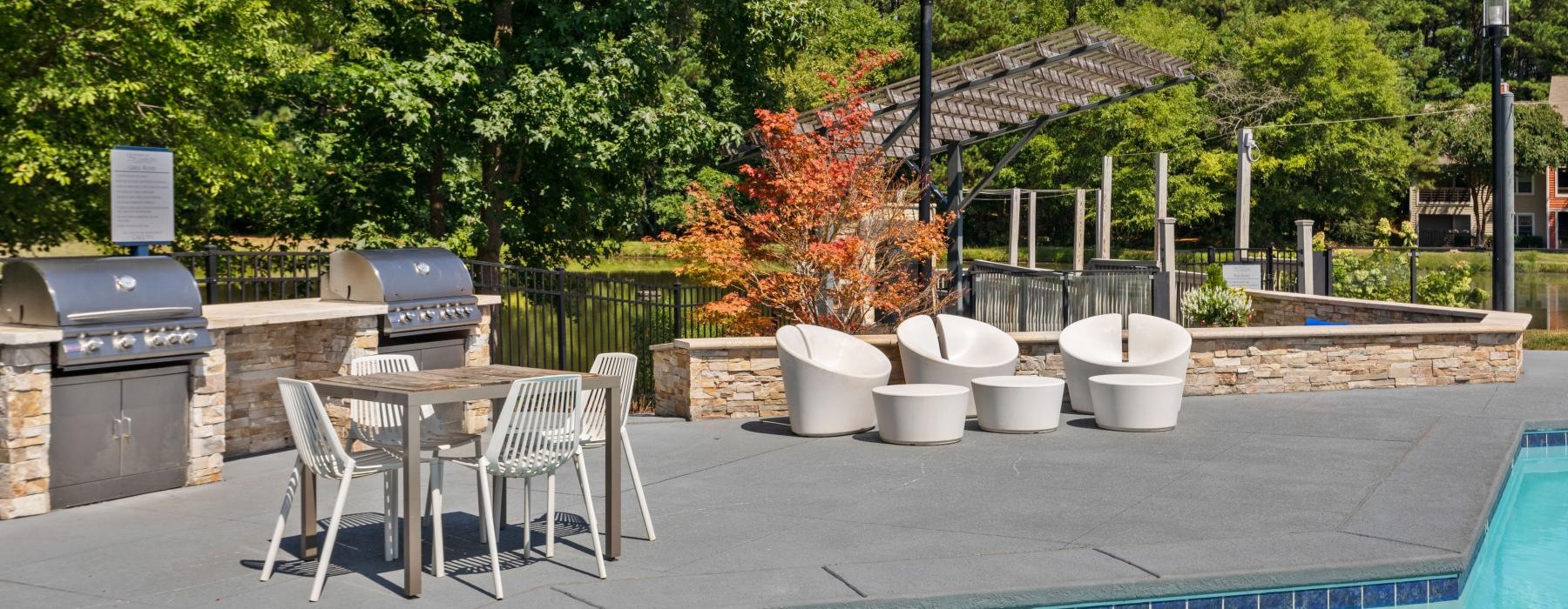 a pool with a table and chairs by it and trees in the back